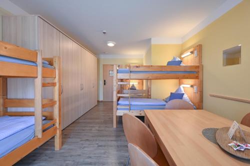 a room with bunk beds and a table and chairs at Rote Villa Füssen in Füssen