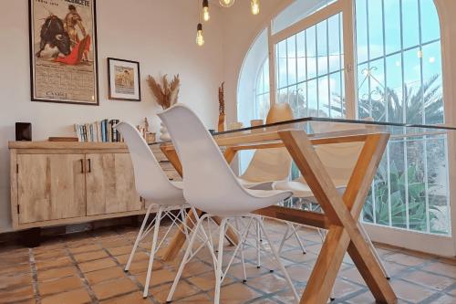 comedor con mesa de cristal y sillas blancas en El Bruni - modern villa close to the beach in Benissa, en Pedramala