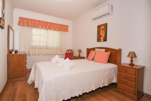 una camera da letto con un letto con lenzuola bianche e una finestra di Apartamento T2 em condomínio fechado. ad Albufeira