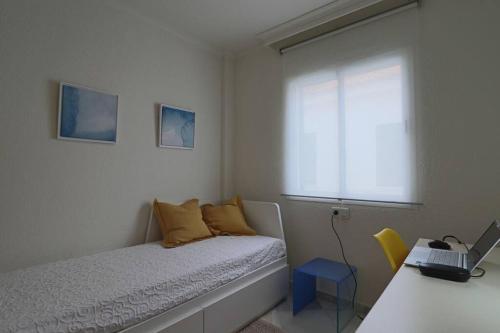 um quarto com uma cama e uma secretária com um computador portátil em Apartamento Toledo 8 em El Rompido