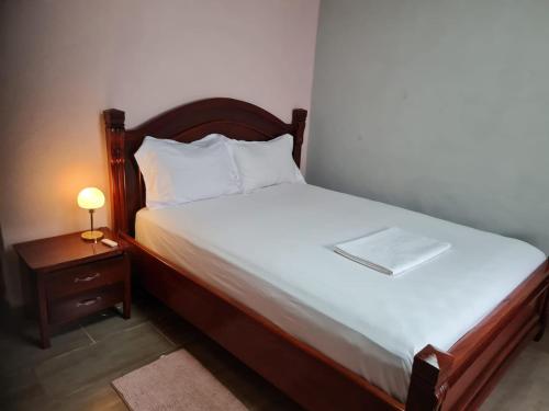 a bedroom with a bed and a night stand with a lamp at ND SMART RESIDENCE in Limbe