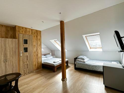 a room with two beds and a table and a tv at Pokoje na Jasełkowej in Szczecin