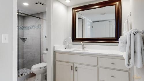 a bathroom with a sink and a toilet and a mirror at Beachfront - Renovated - Gulf view Bedroom - FLPCB5 in Panama City Beach