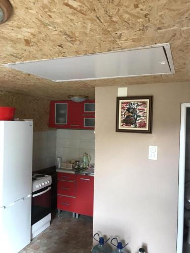 uma cozinha com armários vermelhos e um frigorífico branco em Vikendica Komovi em Andrijevica