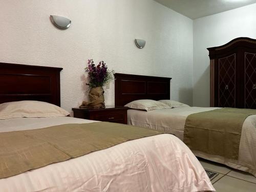 a bedroom with two beds and a vase of flowers at Hotel El Beso De Calixto in Guanajuato