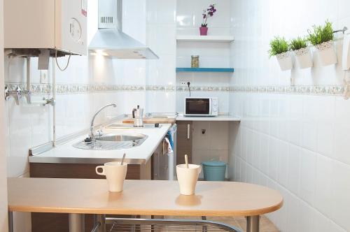 a small kitchen with a table and a sink at Apartamentos Catedral Plaza 3000 in Granada