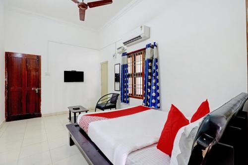 um quarto com uma cama com almofadas vermelhas e uma televisão em OYO K B Residency em Chennai