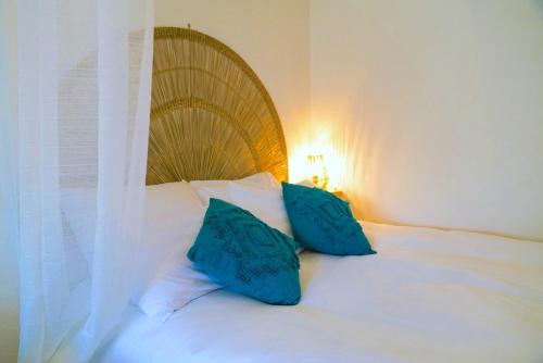 a white bed with two blue pillows on it at Douceur Angevine in Angers