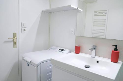 La salle de bains blanche est pourvue d'un lavabo et d'un miroir. dans l'établissement Douceur Angevine, à Angers