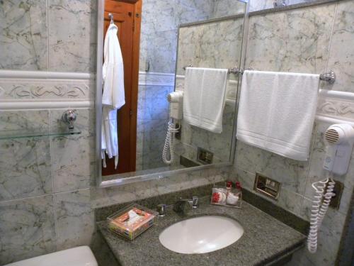 a bathroom with a sink and a mirror and a phone at Hotel Akaskay in Nova Friburgo