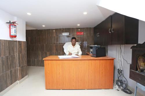 un hombre sentado en un mostrador en una habitación en Hotel Manoj, en Jāmul