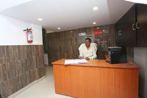 a man sitting at a counter in an office at Hotel Manoj in Jāmul