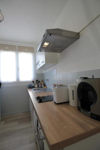 a kitchen with a wooden counter top and two windows at Grand Parking gratuit, De 1 à 4 personnes, Tout équipé, Netflix, Amazon Prime Gratuits et Illimités, Matelas Emma, Lave Linge, Vue sur la Vallée, RDC in Pont-Hébert
