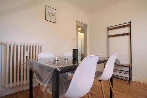 a dining room with a table and white chairs at Grand Parking gratuit, De 1 à 4 personnes, Tout équipé, Netflix, Amazon Prime Gratuits et Illimités, Matelas Emma, Lave Linge, Vue sur la Vallée, RDC in Pont-Hébert