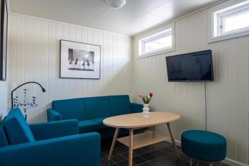 a waiting room with blue chairs and a table and a tv at Mo Gjestegård in Mo i Rana
