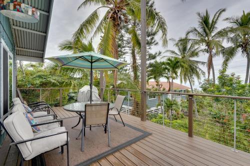 a deck with a table and chairs and an umbrella at Breezy Kailua-Kona Bungalow with Lanai and Ocean View! in Kailua-Kona