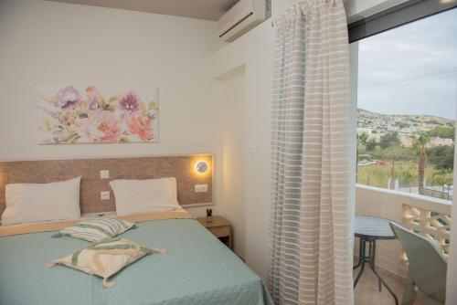 a bedroom with a bed and a large window at Tsaner Apartment and Rooms in Matala