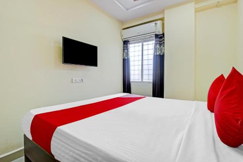 a bedroom with a bed with red pillows and a tv at OYO Adhin Residency in Hyderabad