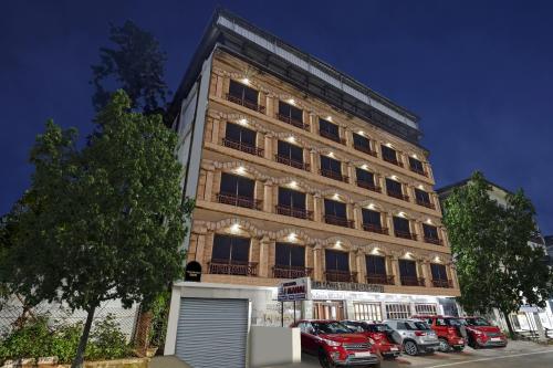 a tall building with cars parked in front of it at Townhouse OAK Hotel Belsons Taj Mahal in Hyderabad