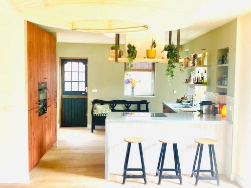 a kitchen with two bar stools and a counter top at 30 steps to sand.. Light and spacious family villa in Zandvoort