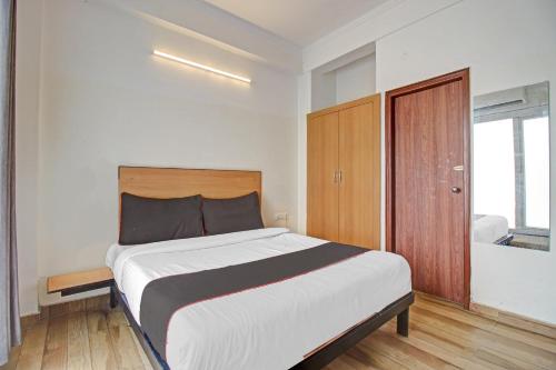 a bedroom with a large bed and a wooden door at Super Townhouse Kachnar House Vikas Nagar in Lucknow