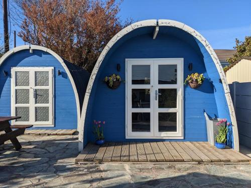 uma casa azul com portas brancas e um alpendre de madeira em A house and a half on Beara peninsula em Castletownbere
