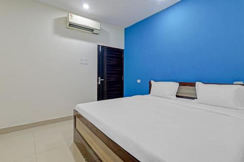 ein Schlafzimmer mit einem weißen Bett und einer blauen Wand in der Unterkunft OYO Hotel Rudra Palace Near Phoenix United Lucknow in Charbagh