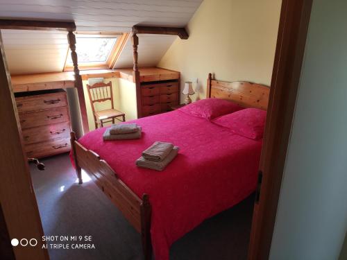 - une chambre avec un lit avec un couvre-lit rouge et une valise dans l'établissement Gîte Le Grenier Cottage anglais Morbihan, à Réminiac