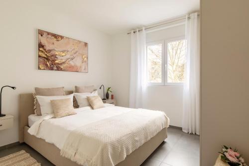 a white bedroom with a bed and a window at Lugano Superior Suites - Free Parking in Lugano