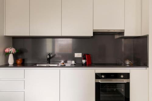 a kitchen with white cabinets and a sink at Lugano Superior Suites - Free Parking in Lugano