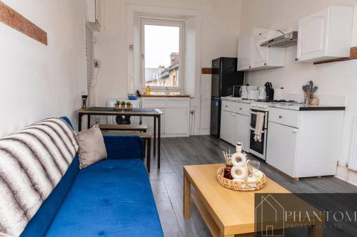 a living room with a blue couch and a kitchen at Complex Suite in Glasgow