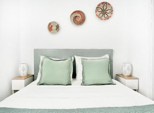 una camera da letto con un letto bianco con cuscini verdi di Apartamento Atardecer en Menorca Son Parc Vista al campo de golf a Son Parc