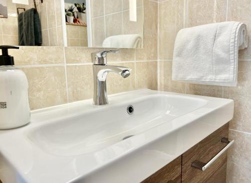 een witte wastafel in een badkamer met een zeepdispenser bij Apartamento Atardecer en Menorca Son Parc Vista al campo de golf in Son Parc