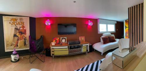 a living room with a couch and a tv in a room at Love room - love Abella box, location adulte in Saint-Étienne-au-Mont