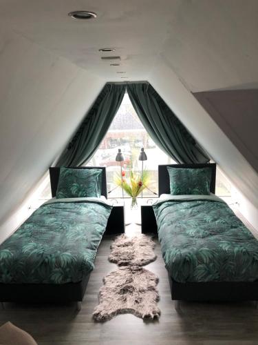 two beds in a room with a window at B&B Bij Arjan in Terborg