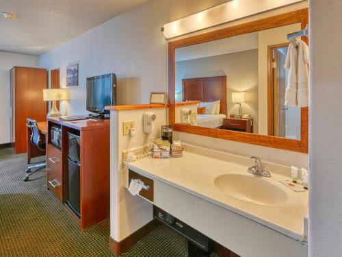 a hotel room with a bathroom with a sink and a mirror at Yellowstone River Inn & Suites in Livingston