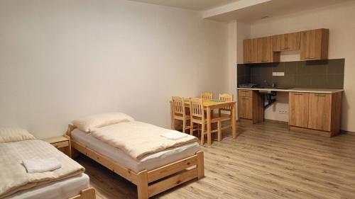 a room with two beds and a kitchen with a table at Apartmány Javorník in Javorník