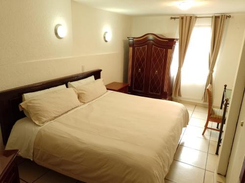 a bedroom with a bed with white sheets and a window at Hotel El Beso De Calixto in Guanajuato