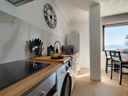 a kitchen with a counter and a clock on the wall at Mirador do Mar, encima de la playa in Moaña