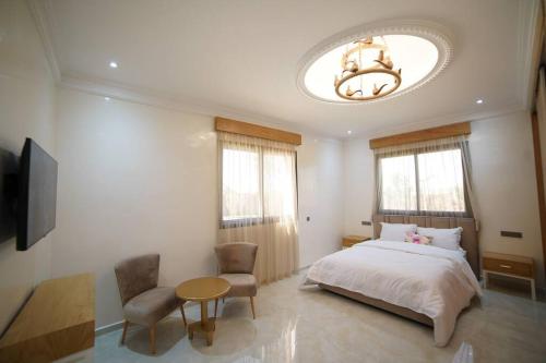 1 dormitorio con cama, mesa y lámpara de araña en Villa Écologique à Proximité de la Plage, en Agadir