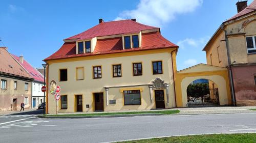 a yellow building with a red roof on a street at Apartmány Javorník in Javorník