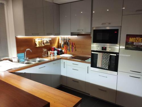 a kitchen with white cabinets and a sink and a microwave at Italia House in Fót