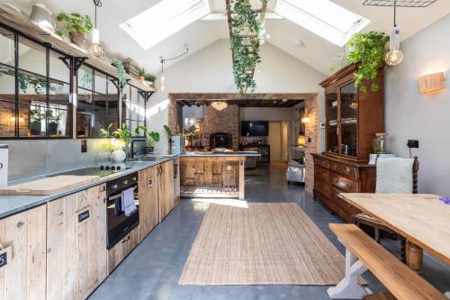 uma grande cozinha com armários de madeira e uma mesa em The Walled Garden at Cheshire Boutique Bathhouse em Nantwich