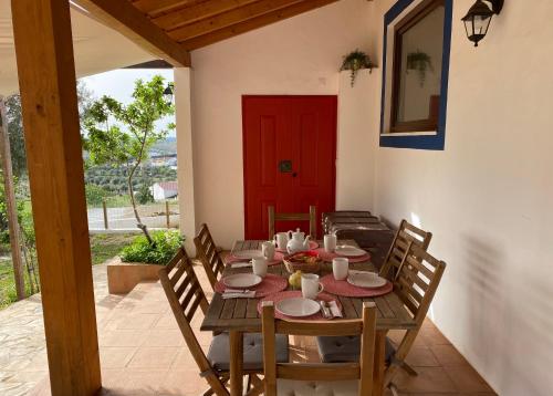 a wooden table with chairs and a red door at Montado Village in Portel