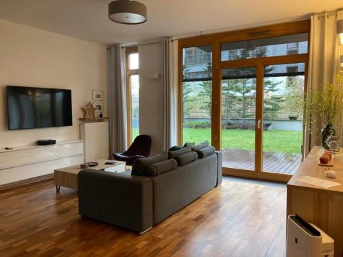 ein Wohnzimmer mit einem Sofa und einem TV in der Unterkunft WILANOWSKA apartment & garden in Warschau