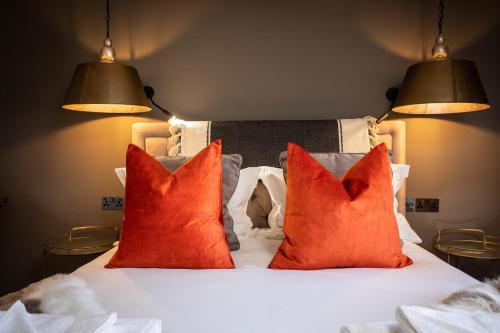 a bed with two orange pillows and two lamps at The Cocktail Lounge at Cheshire Boutique Bathhouse in Nantwich