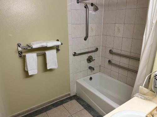 a bathroom with a tub and a shower with towels at Rivera Inn & Suites Motel in Pico Rivera