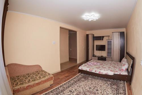 a small bedroom with a bed and a couch at Венеция in Petropavlovsk