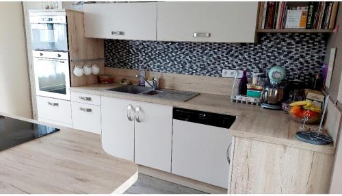 une cuisine avec des armoires blanches et un évier dans l'établissement Maison avec jardin pour 7 pers à Vibraye - Perche 2h de Paris - 45 min circuit 24h du Mans, à Vibraye