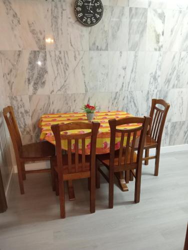 a dining room table with four chairs and a clock on the wall at Apartamento Alvares Cabral in Vila Nova de Gaia